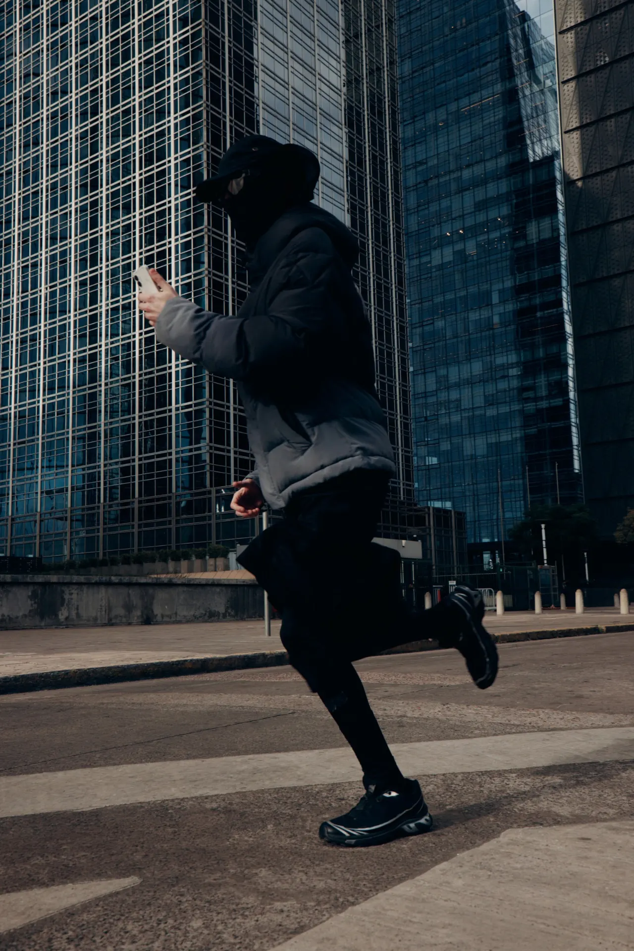 A person walking on a street in front of glass buildings