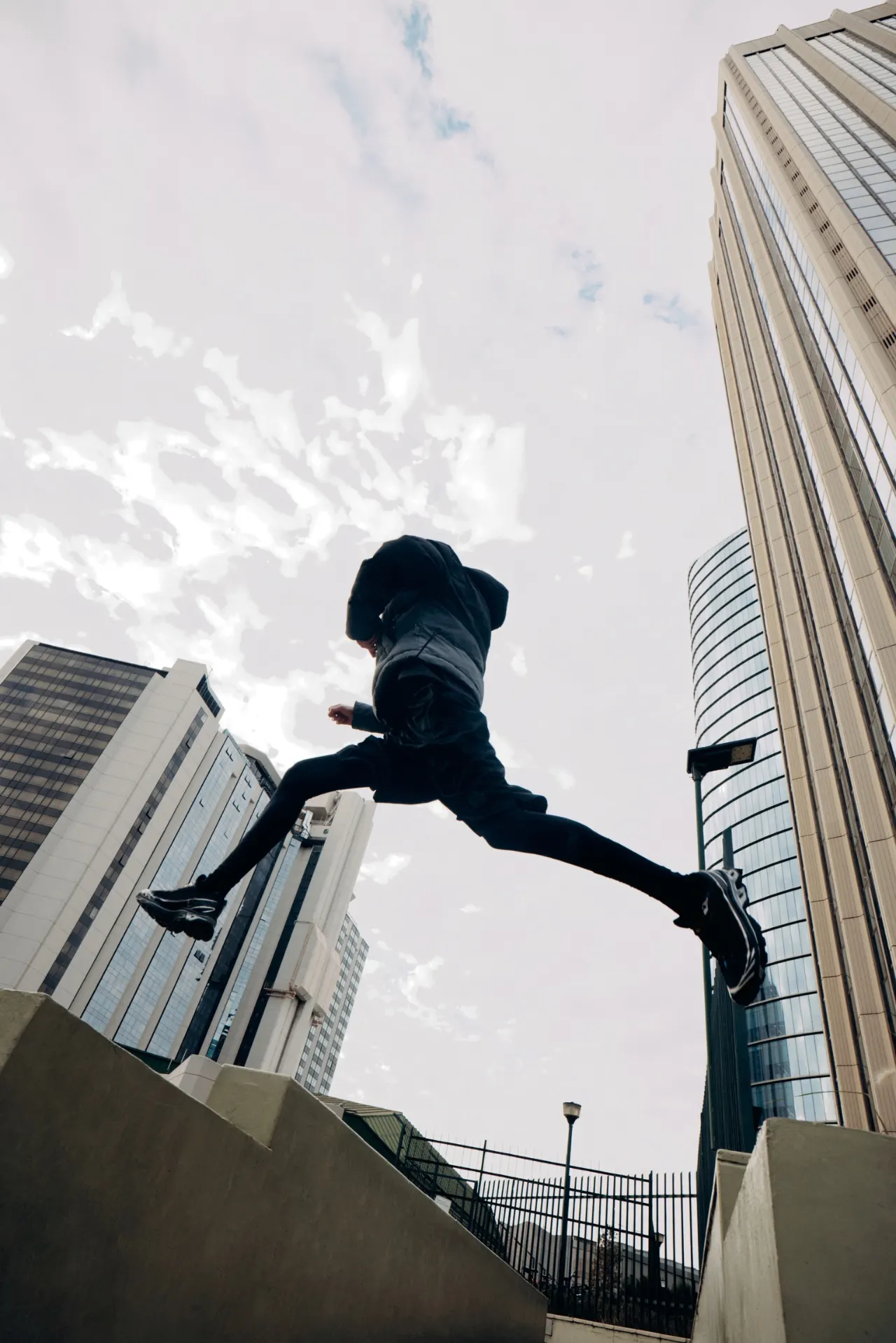 A person leaping between tall buildings against the sky
