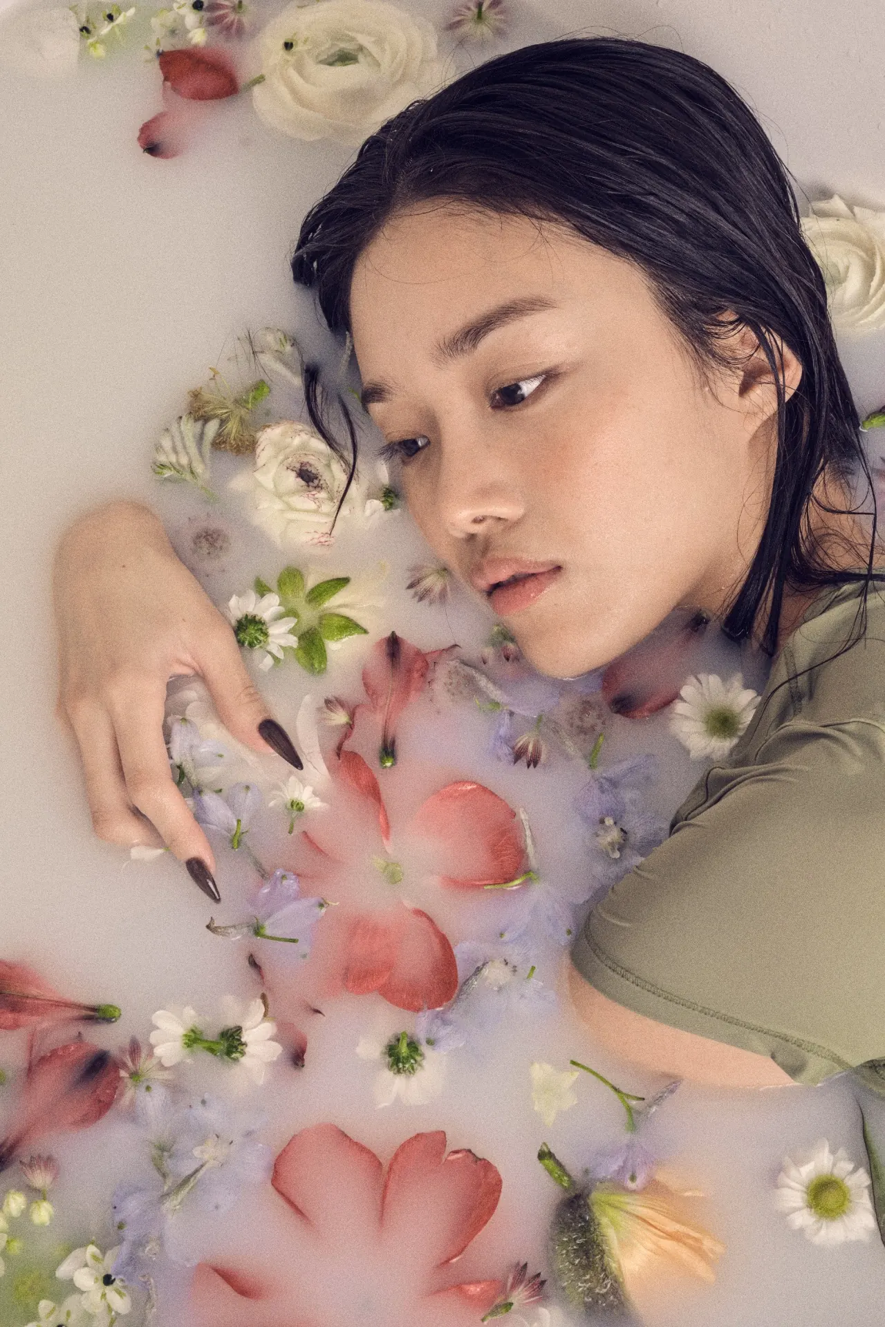 花びらが浮かぶ水に身を寄せる女性
