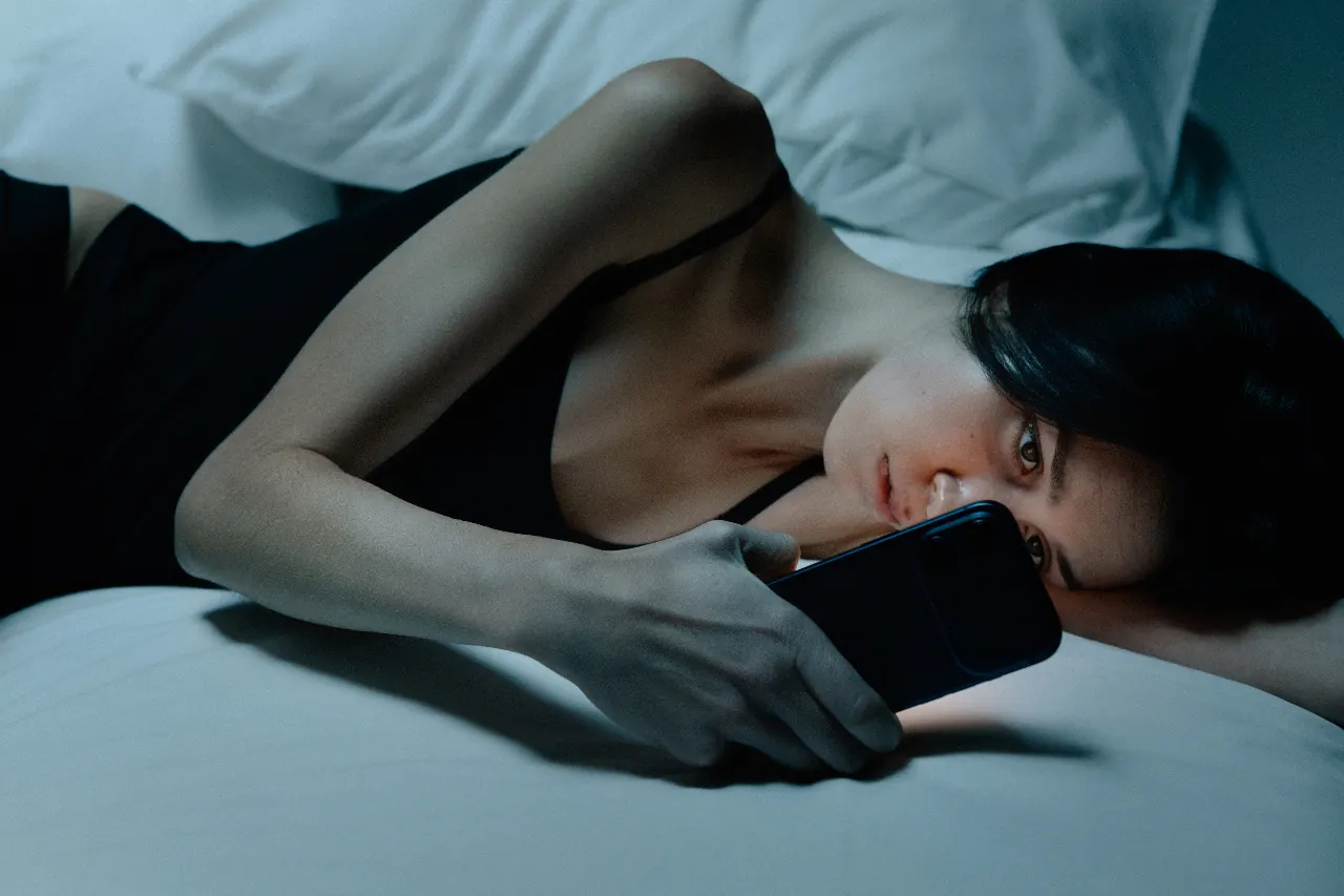 A woman lying in bed looking at her phone