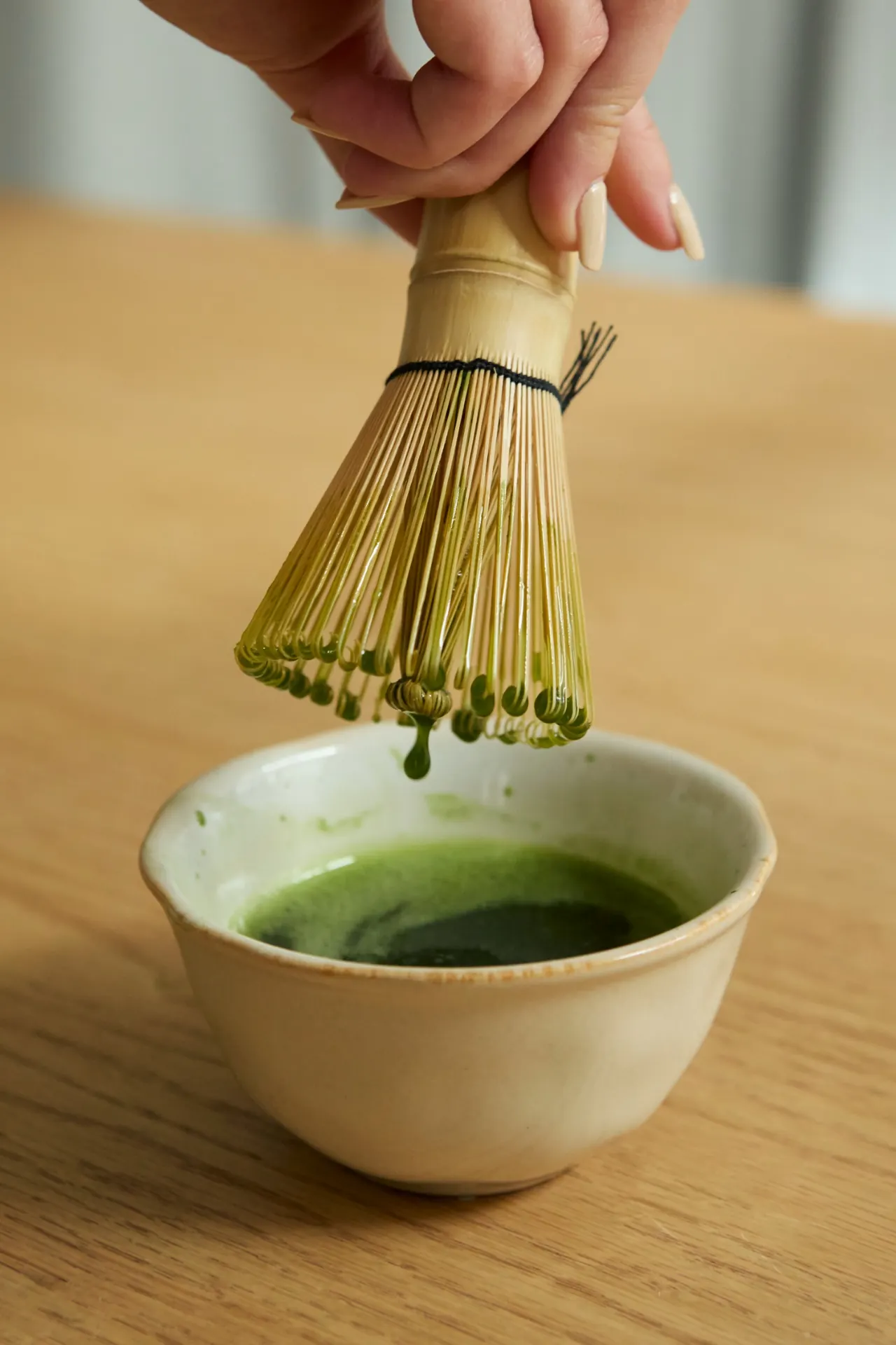 A bamboo whisk above a bowl of matcha